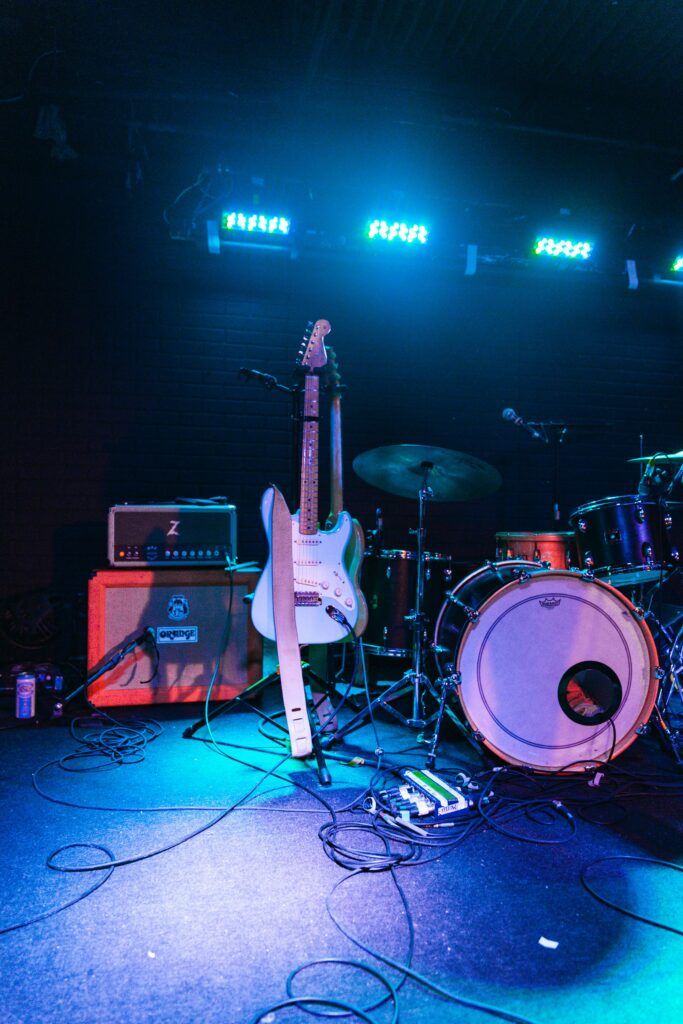 pexels-photo-1943411-1943411 Electric guitar and drum set on an illuminated live music stage, ready for performance.